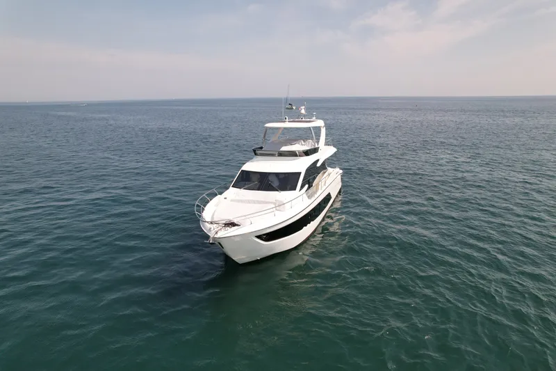 Slide: The Image of The 2022 Absolute 62 Fly glides elegantly over calm waters under a clear sky. - 1