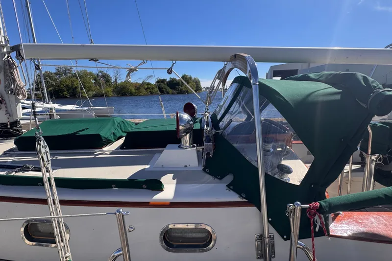 Slide: The Image of 1986 Tashing Tashiba 31 sailboat with green covers docked by a serene lake. - 5