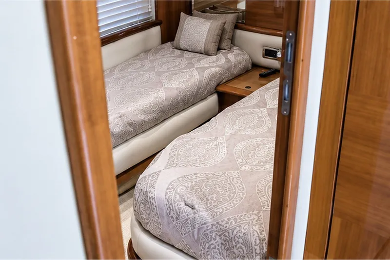 Slide: The Image of Luxurious twin cabin interior on a 2004 Azimut 62 yacht, featuring elegant bedding and wood finishes. - 14