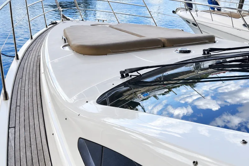 Slide: The Image of 2004 Azimut 62 yacht deck with sun pad, reflecting blue sky and clouds. - 39