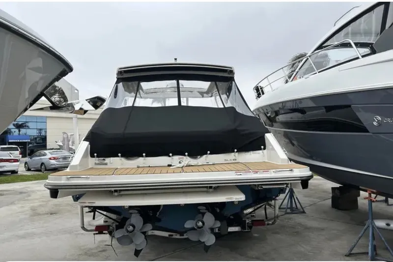 Slide: The Image of 2024 Sea Ray SLX 310 boat with covered deck, docked between other boats. - 22
