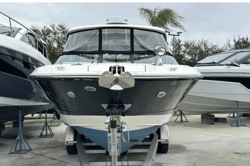 Slide: The Image of 2024 Sea Ray SLX 310 boat on trailer, parked outdoors, surrounded by other boats. - 19