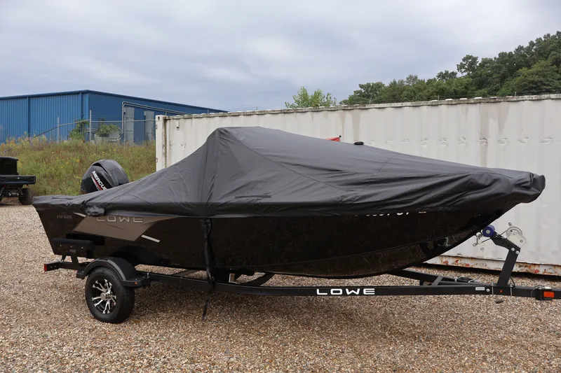 Slide: The Image of 2022 Lowe Fishing Machine 1625WT boat covered, parked on gravel near a shipping container. - 43