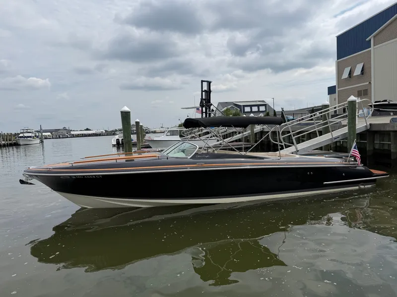 Slide: The Image of 2020 Chris-Craft Corsair 34 in the water, featuring sleek black paint and wood accents. - 18