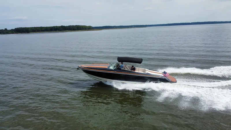 Slide: The Image of 2020 Chris-Craft Corsair 34 cruising on a calm lake, featuring an American flag. - 10