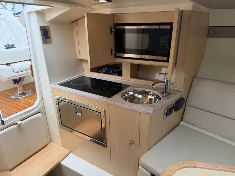 Slide: The Image of The interior of a 2020 Chris-Craft Corsair 34 features a compact kitchen with a stove, sink, and microwave. - 43
