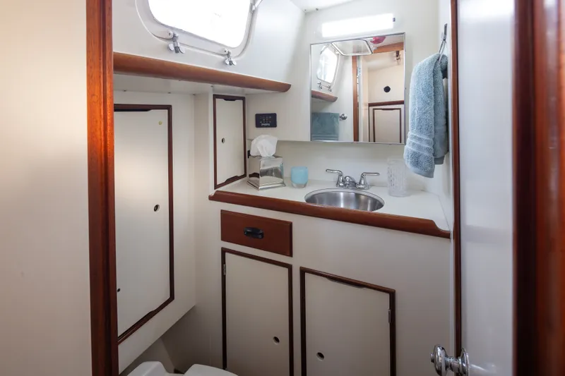 Slide: The Image of Vintage 1970 Sparkman & Stephens 57 yacht bathroom with sink, mirror, and storage cabinets. - 12