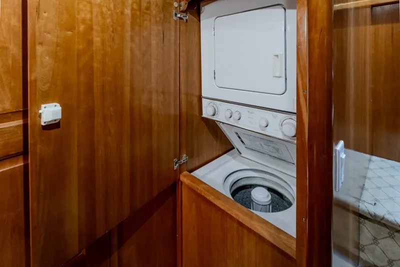 Slide: The Image of 2004 Navigator Pilothouse laundry area with stacked washer and dryer in wooden cabinet. - 32