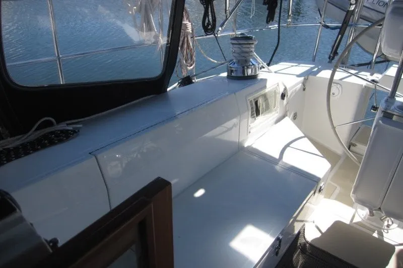 Slide: The Image of Cockpit of 2014 Outbound 46 sailboat with seating and steering wheel, docked on calm water. - 27