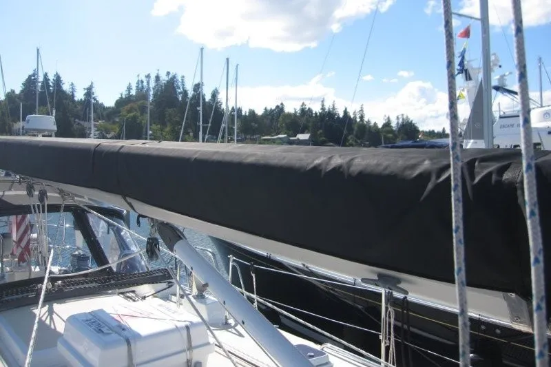 Slide: The Image of Sailboat deck view of 2014 Outbound 46, featuring covered boom and marina backdrop. - 42