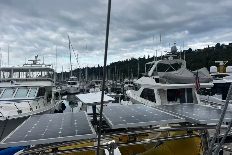 Slide: The Image of Boats docked at a marina under cloudy skies, featuring solar panels on a Hylas 49 yacht. - 61