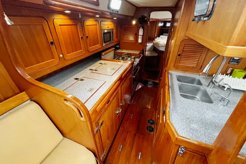 Slide: The Image of Luxurious 1994 Hylas 49 yacht interior with wooden cabinetry and modern kitchen amenities. - 8