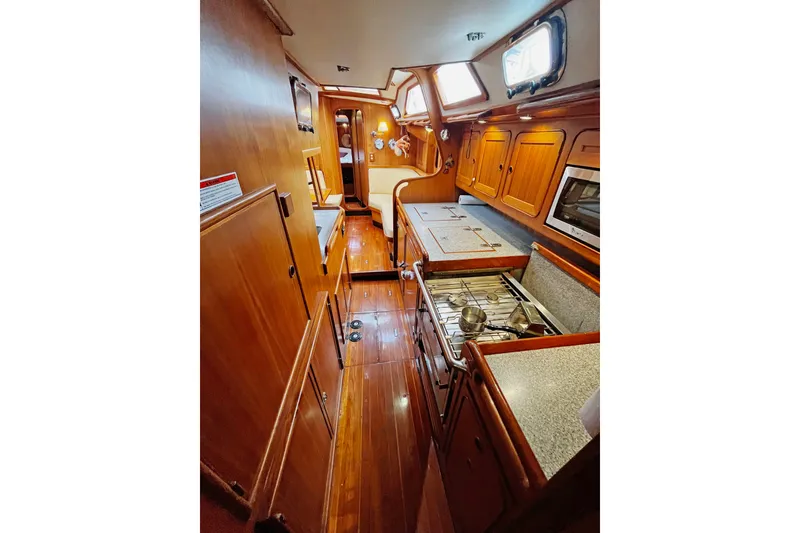 Slide: The Image of Interior of a 1994 Hylas 49 yacht featuring a wooden galley and cozy cabin space. - 10