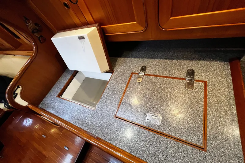 Slide: The Image of The galley of a 1994 Hylas 49 with a gray countertop and wooden cabinets. - 24
