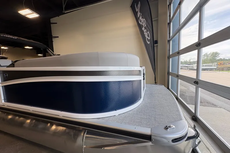 Slide: The Image of 2027 Premier 220 Sunscape RL - DL pontoon boat displayed indoors near large windows. - 3