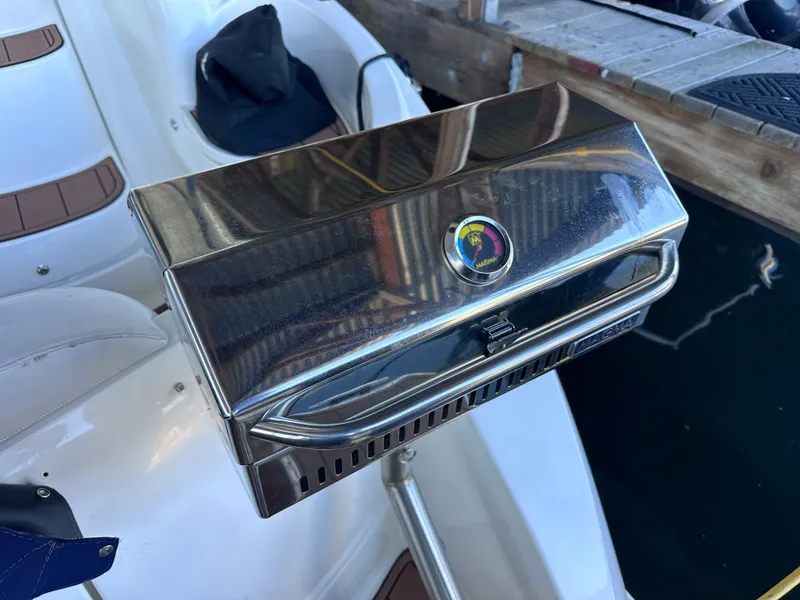 Slide: The Image of A shiny stainless steel grill on a boat, surrounded by white seats and a wooden dock. - 31