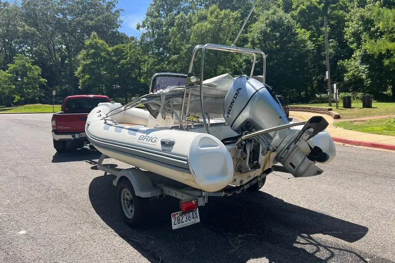 Slide: The Image of 2019 Brig Navigator 485 inflatable boat on trailer, parked near trees and red truck. - 18