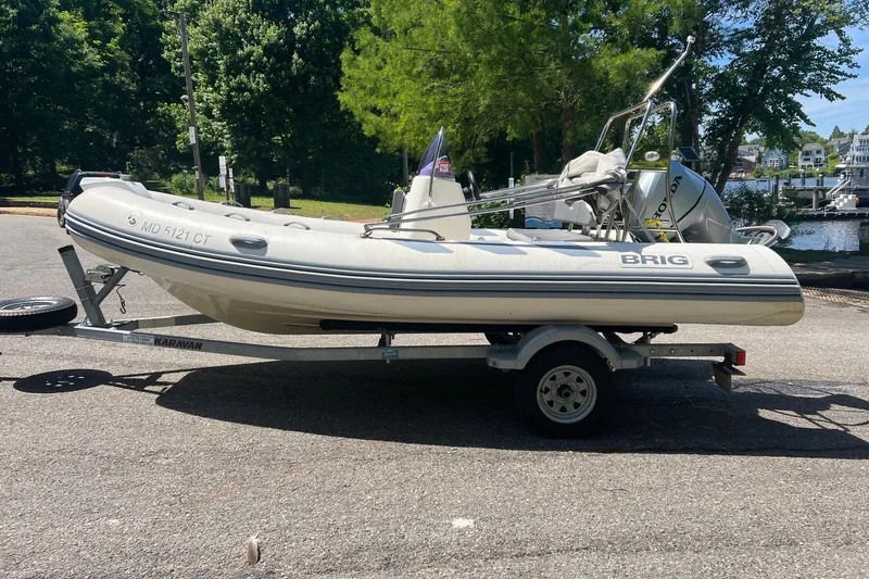 Slide: The Image of 2019 Brig Navigator 485 inflatable boat on trailer, parked near a scenic waterfront. - 17