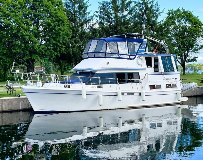 The Image of 1987 Bestway Labelle 40 docked by the shore with trees in the background. - 1
