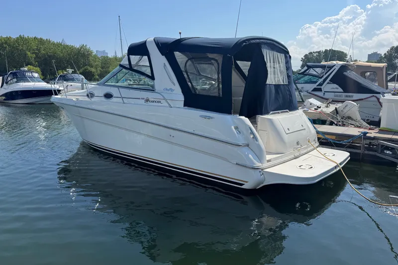 The Image of 2001 Sea Ray 290 Sundancer boat docked in a marina under a clear blue sky. - 1