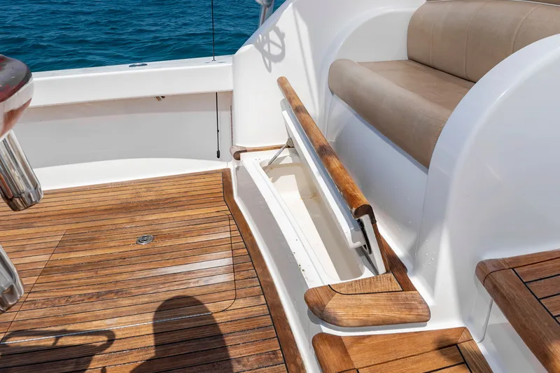 Slide: The Image of The image shows the teak deck of a 2018 Viking Sport Tower with a bench seat and storage. - 13