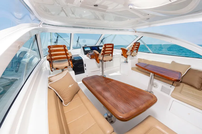 Slide: The Image of The image shows the cockpit of a 2018 Viking Sport Tower yacht with wooden tables and leather seats. - 15