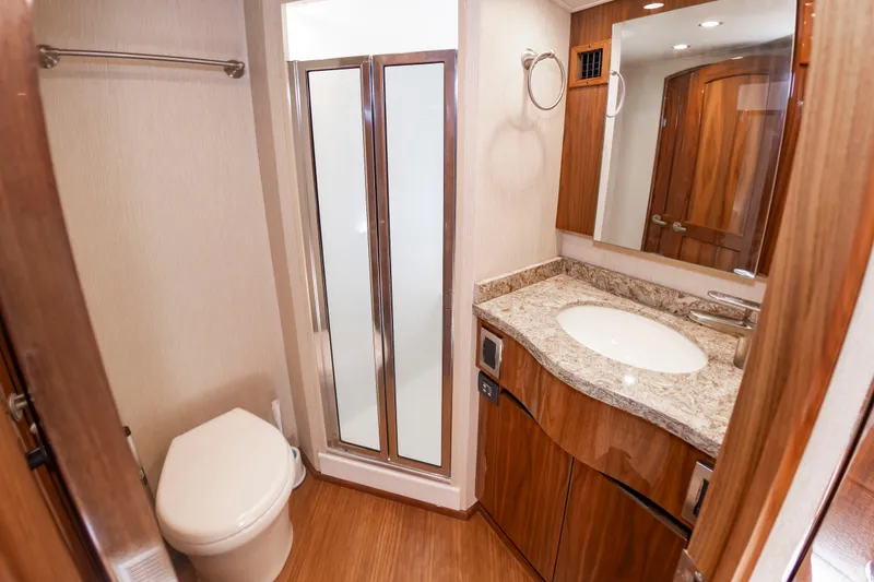 Slide: The Image of Bathroom with wood flooring, toilet, shower, and vanity with mirror. - 38