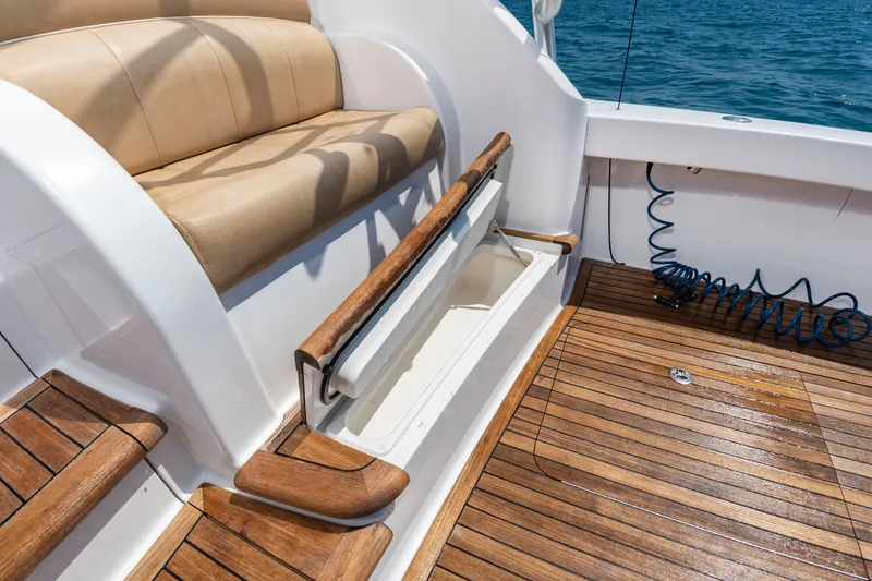 Slide: The Image of The image shows the teak deck of a 2018 Viking Sport Tower with a bench seat and storage. - 12