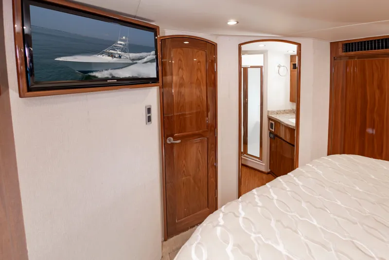 Slide: The Image of Interior of a luxurious cabin with wooden doors, a TV, and a bed with a white comforter. - 37