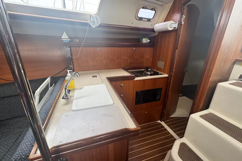 Slide: The Image of Interior of a 2006 Hunter 31 sailboat featuring a compact kitchen area. - 25