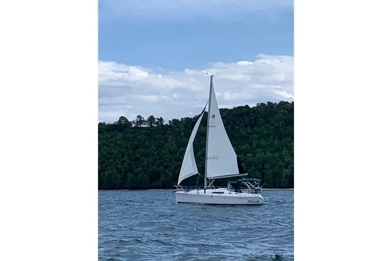 Slide: The Image of Sailboat on a lake with a wooded shoreline in the background. - 42