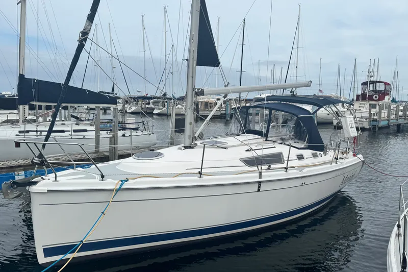 The Image of 2006 Hunter 31 sailboat docked at marina with blue canopy and white hull. - 0
