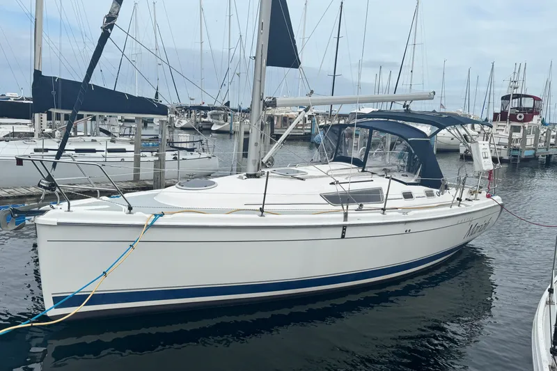 Slide: The Image of 2006 Hunter 31 sailboat docked in a marina, featuring a sleek white hull and blue accents. - 1