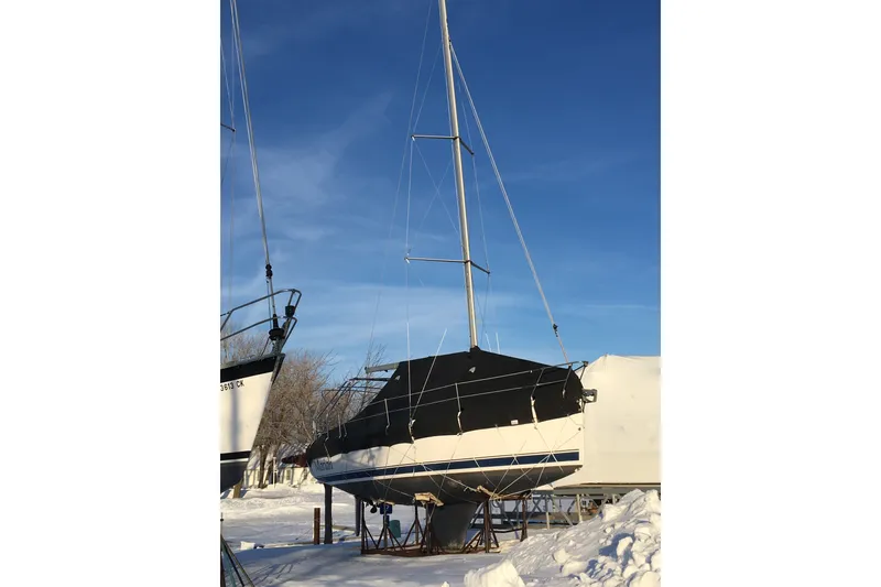 Slide: The Image of 2006 Hunter 31 sailboat on stands in snowy yard under clear blue sky. - 44