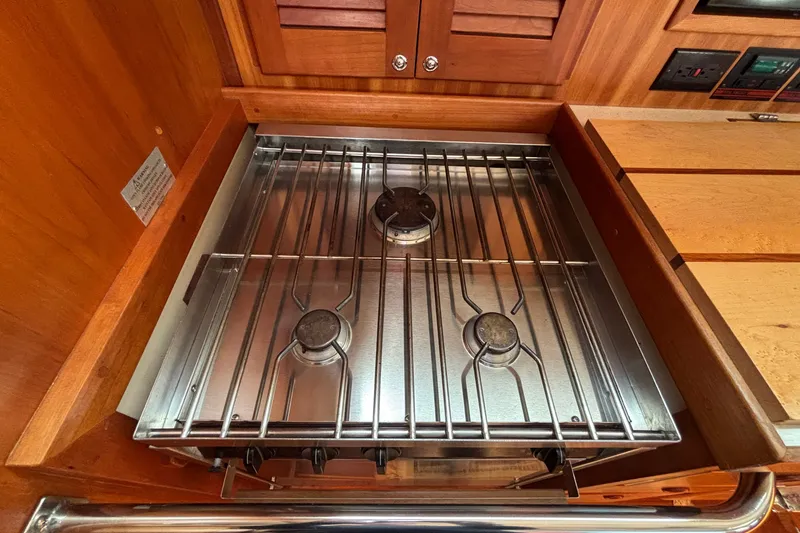 Slide: The Image of Stainless steel stove in 2002 Sabre 402 yacht galley, featuring three burners and wooden cabinetry. - 69