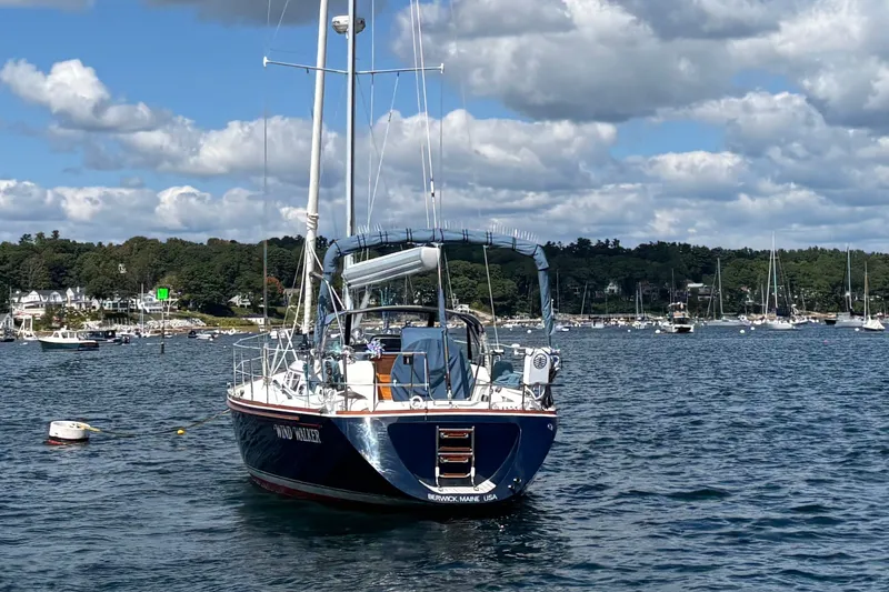 Slide: The Image of 2002 Sabre 402 sailboat anchored in scenic harbor with blue skies and distant shoreline. - 14