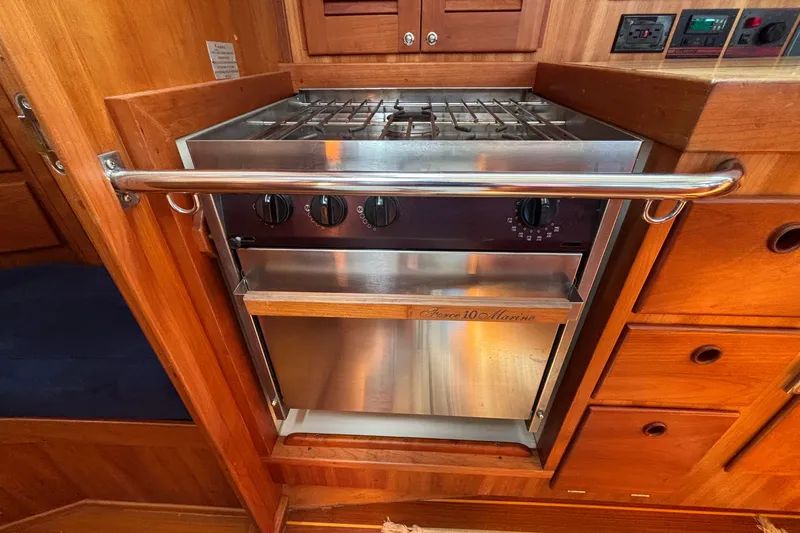 Slide: The Image of Galley stove in 2002 Sabre 402 yacht, featuring stainless steel finish and wooden cabinetry. - 70