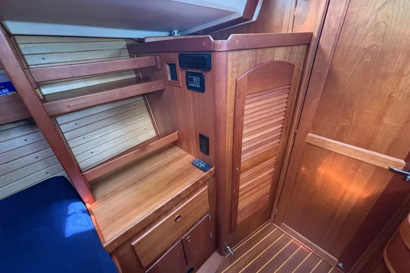 Slide: The Image of Interior of a 2002 Sabre 402 sailboat featuring wooden cabinetry and blue upholstery. - 59