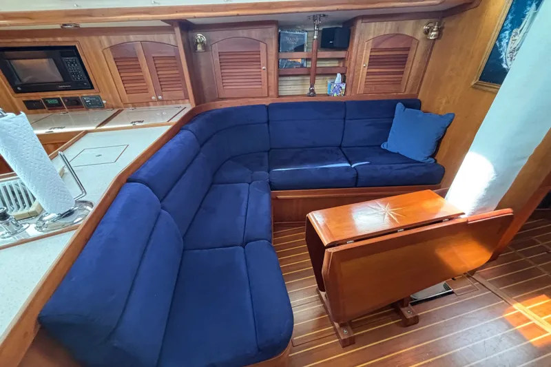 Slide: The Image of Luxurious Sabre 402 yacht interior with blue cushioned seating and wooden table, 2002 model. - 52
