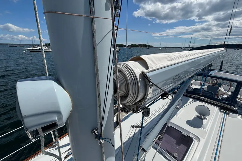 Slide: The Image of Sailboat deck view of 2002 Sabre 402, featuring mast and boom against a scenic harbor backdrop. - 27
