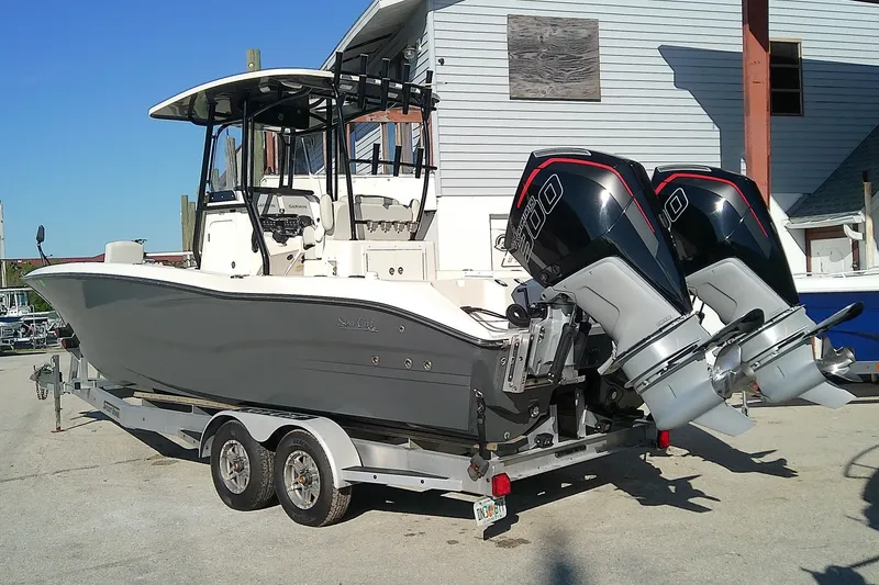 Slide: The Image of 2022 Sea Cat 260 boat on trailer with dual outboard engines, parked outdoors. - 2