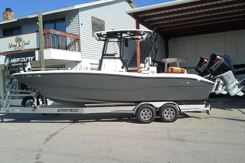 Slide: The Image of 2022 Sea Cat 260 boat on trailer outside a marine shop, featuring twin engines. - 1