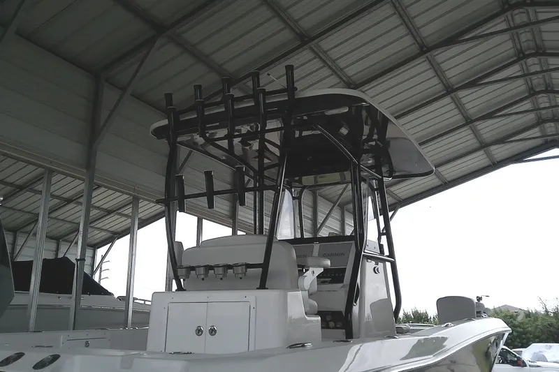 Slide: The Image of A 2022 Sea Cat 260 under a covered area. It features a sturdy T-top and fishing rod holders. - 26