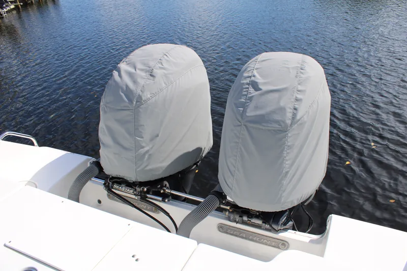 Slide: The Image of 2019 Sea Hunt Gamefish 25 boat with covered twin outboard motors on water. - 32