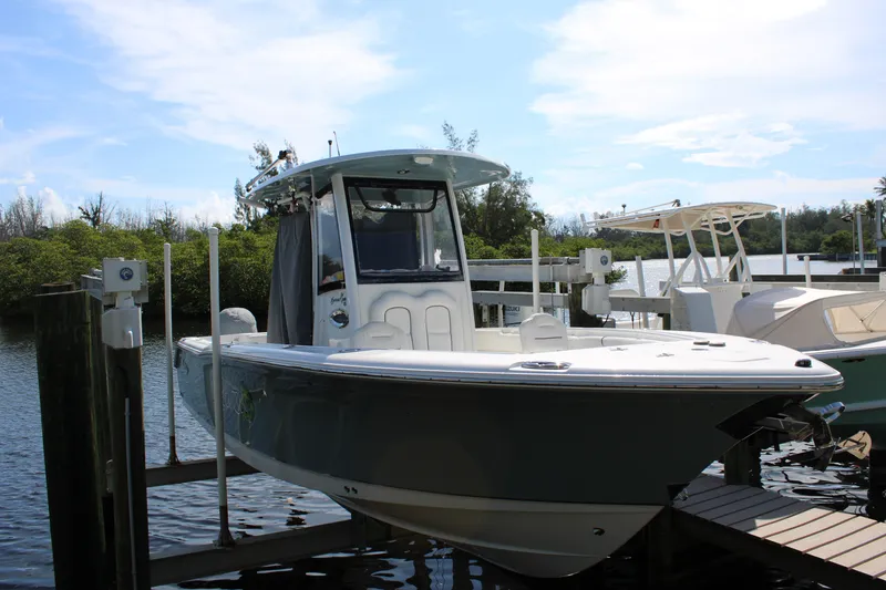Slide: The Image of 2019 Sea Hunt Gamefish 25 boat docked by the water, showcasing sleek design and modern features. - 4
