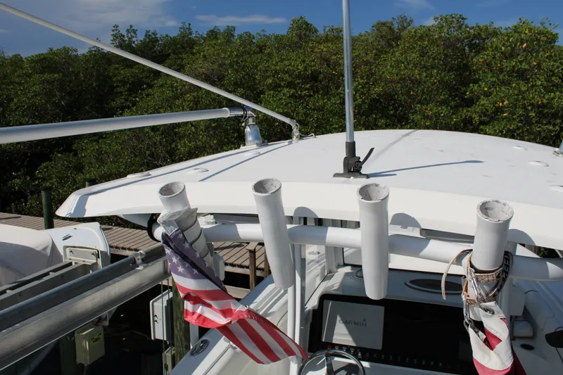 Slide: The Image of 2019 Sea Hunt Gamefish 25 boat with rod holders and American flag, docked near greenery. - 37