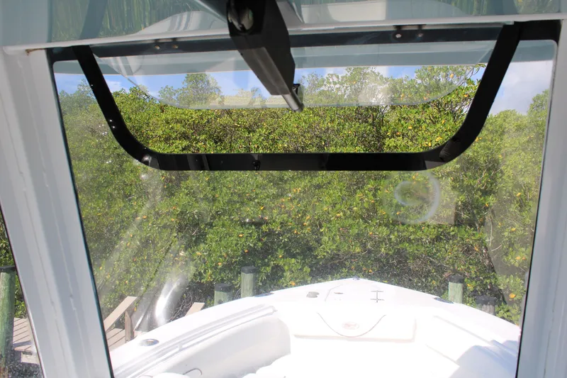 Slide: The Image of 2019 Sea Hunt Gamefish 25 boat windshield view with lush greenery background. - 24