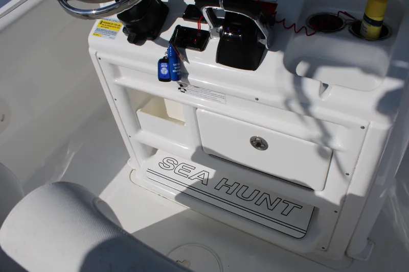 Slide: The Image of 2019 Sea Hunt Gamefish 25 boat console with steering wheel and storage compartments. - 25