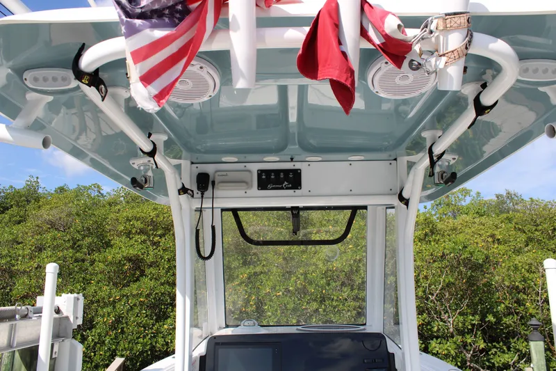 Slide: The Image of 2019 Sea Hunt Gamefish 25 boat console with American flag and lush greenery background. - 15