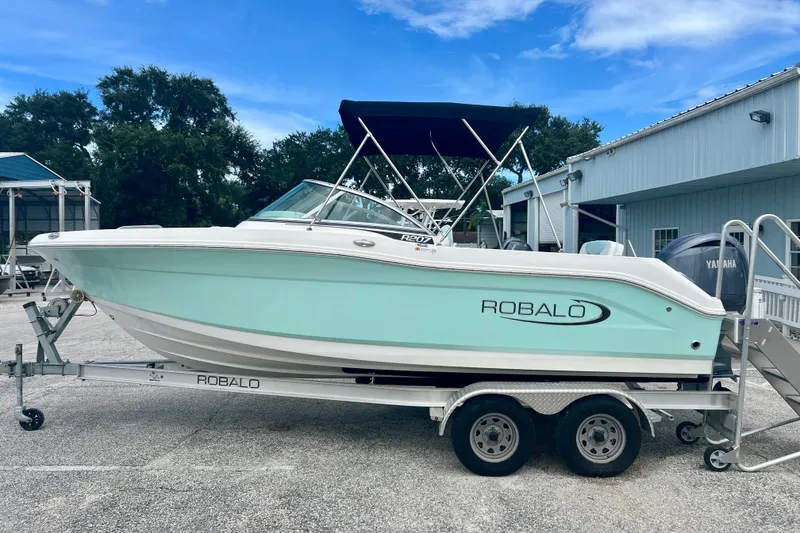 Slide: The Image of 2024 Robalo R207 Dual Console boat on trailer, light blue hull, parked outdoors. - 5